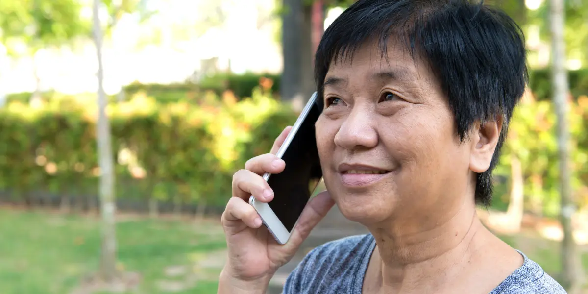 Woman speaking on phone while outdoors in a park